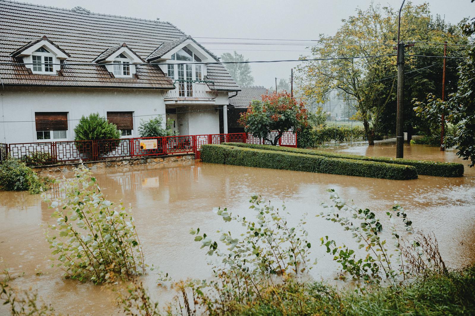 Flood, Flood Insurance, A suburban house surrounded by floodwaters after heavy rain, showing impact of natural disaster.